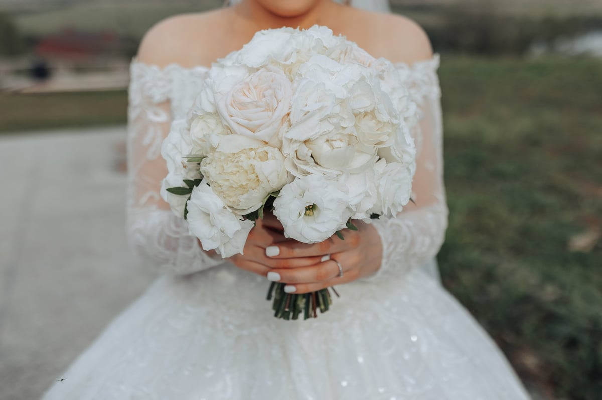 A bride is holding a bouquet of white flowers