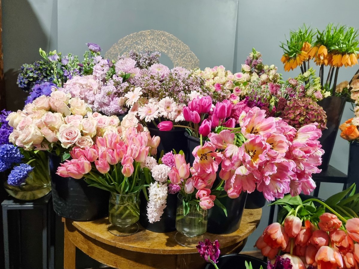 Colorful assortment of fresh flowers displayed in black buckets inside flower shop