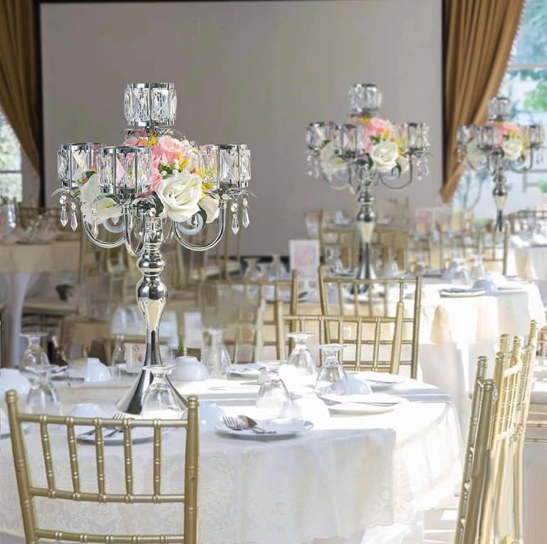 Elegant wedding reception table with crystal candelabra centerpiece, white flowers, gold chiavari chairs, and white linens